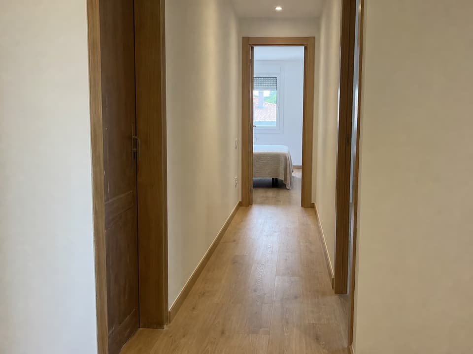 Pasillo renovado con suelo, pintura y carpintería de madera